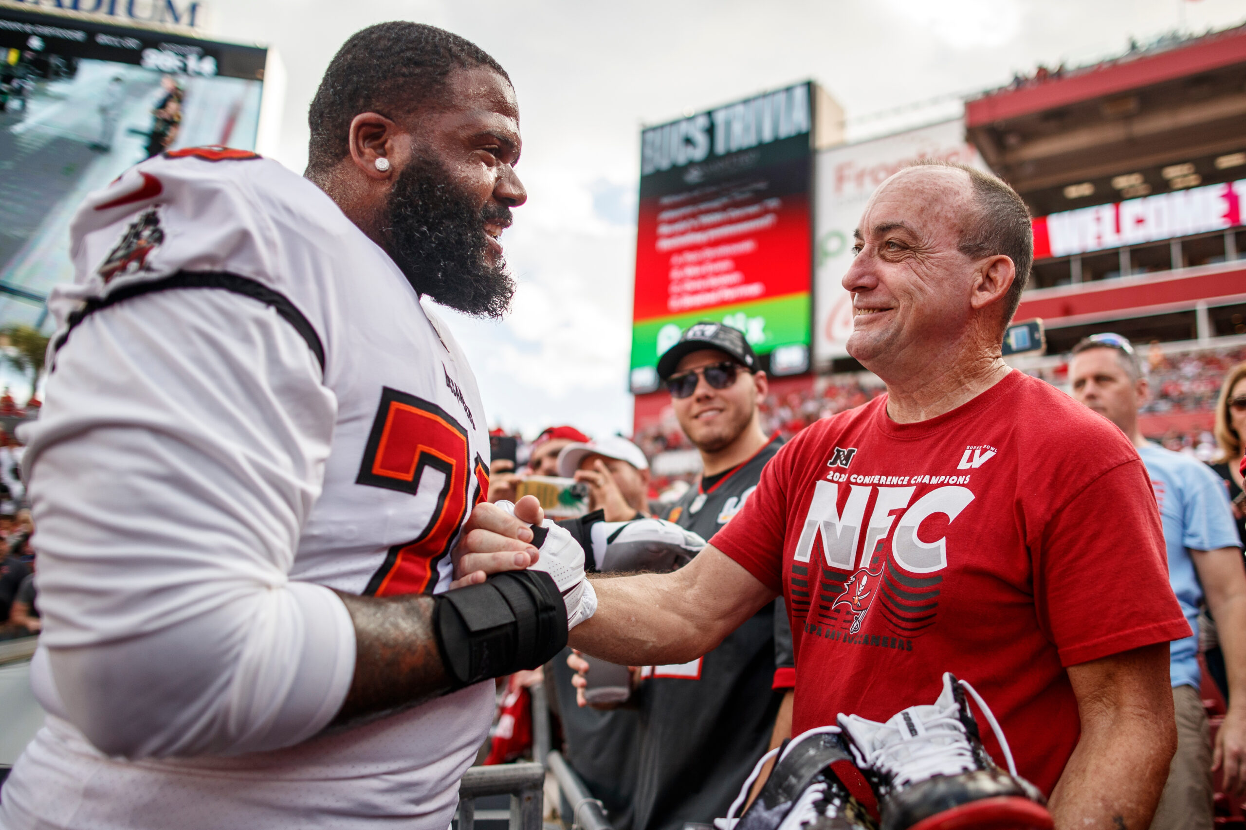 Tampa Bay Buccaneers player Donovan Smith gives custom cleats to Robert DuBoise before the game between the Carolina Panthers and Tampa Bay Buccaneers at Raymond James Stadium in Tampa, Florida, on Jan. 9, 2022. (Image: Kyle Zedaker/Tampa Bay Buccaneers)