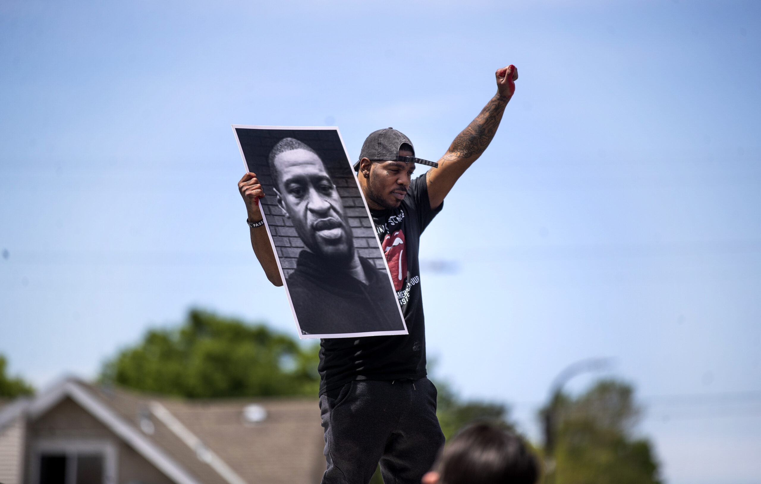 Tony L. Clark holds a photo of George Floyd outside the Cup Food convenience store, near where Floyd was killed, May 28, 2020, in Minneapolis. (Image: Jerry Holt/Star Tribune via AP)