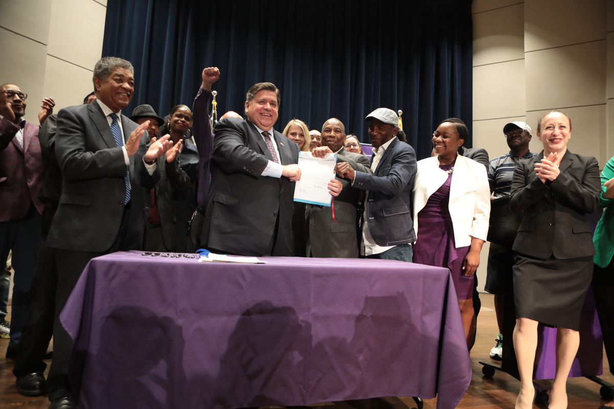 Gov. Pritzker signs deception bill with exonerees, Innocence Project staff and State Attorney Kim Foxx on Thursday, July 15, 2021 in Chicago. (Jean-Marc Giboux/AP Images for Innocence Project)