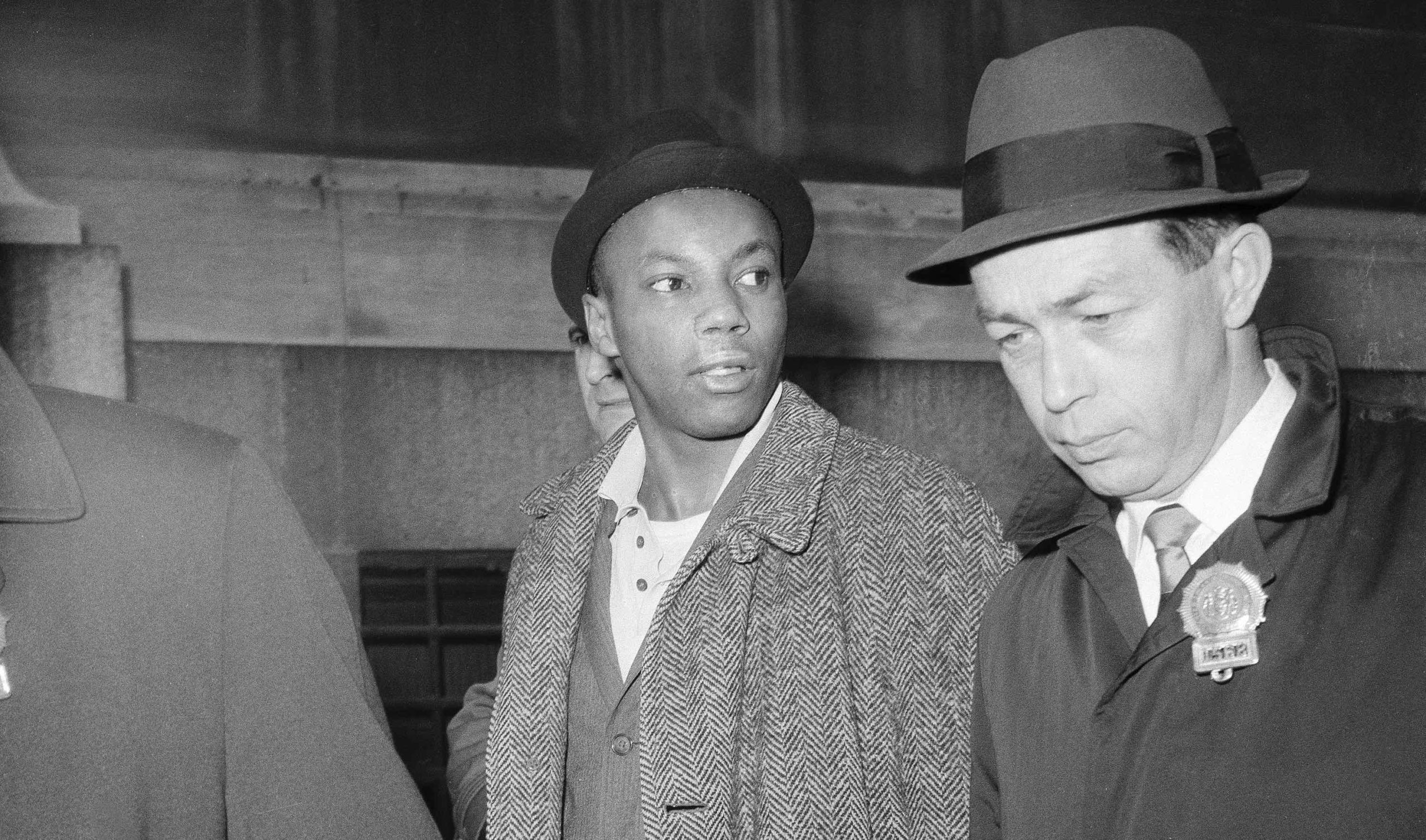 Norman 3X Butler is escorted by detectives at police headquarters at 240 Centre Street after his arrest as a suspect in the assassination of Malcolm X, in New York, Feb. 26, 1965. Butler, who now goes by Muhammad Abdul Aziz, always maintained his innocence. (Image: Associated Press)