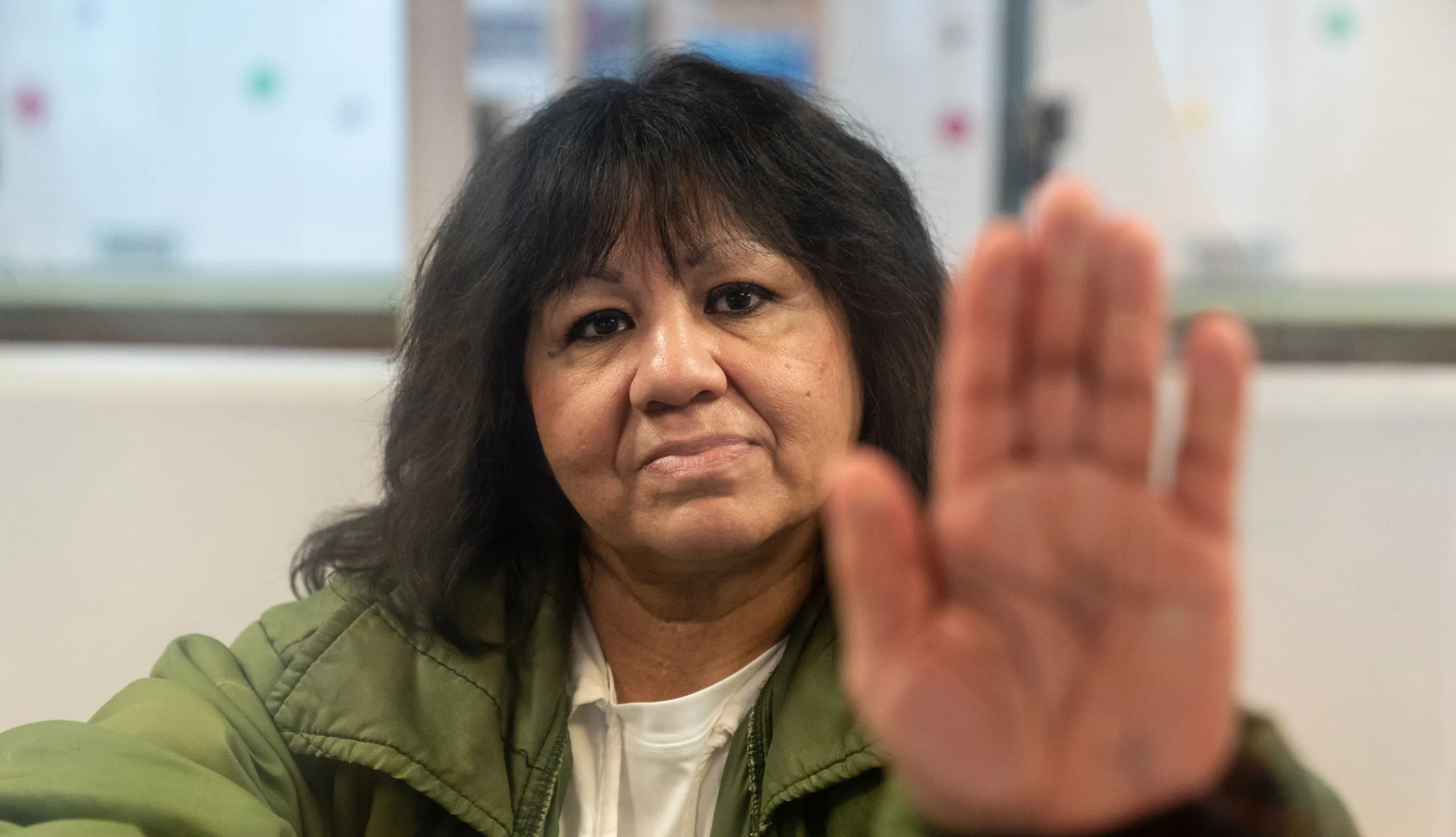 Melissa Lucio poses for a portrait behind glass at the Mountain View Unit in Gatesville, Texas. (Image: Ilana Panich-Linsman for The Innocence Project)