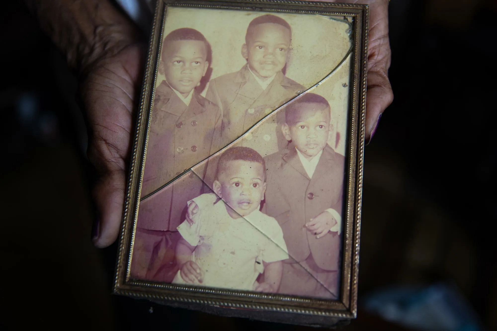 Sandra Reed holding an archival photo of her four sons, including Rodney the baby in white, in her home in Texas in May 2023. (Image: Montinique Monroe/Innocence Project)